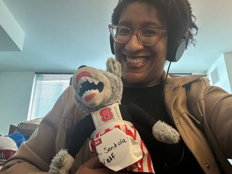 Kristen smiling holding a doll version of NC State University's Mrs. Wuf Mascot she's renamed Mx. Sanfoka Wuf Kristen smiling holding a doll version of NC State University's Mrs. Wuf Mascot she's renamed Mx. Sanfoka Wuf